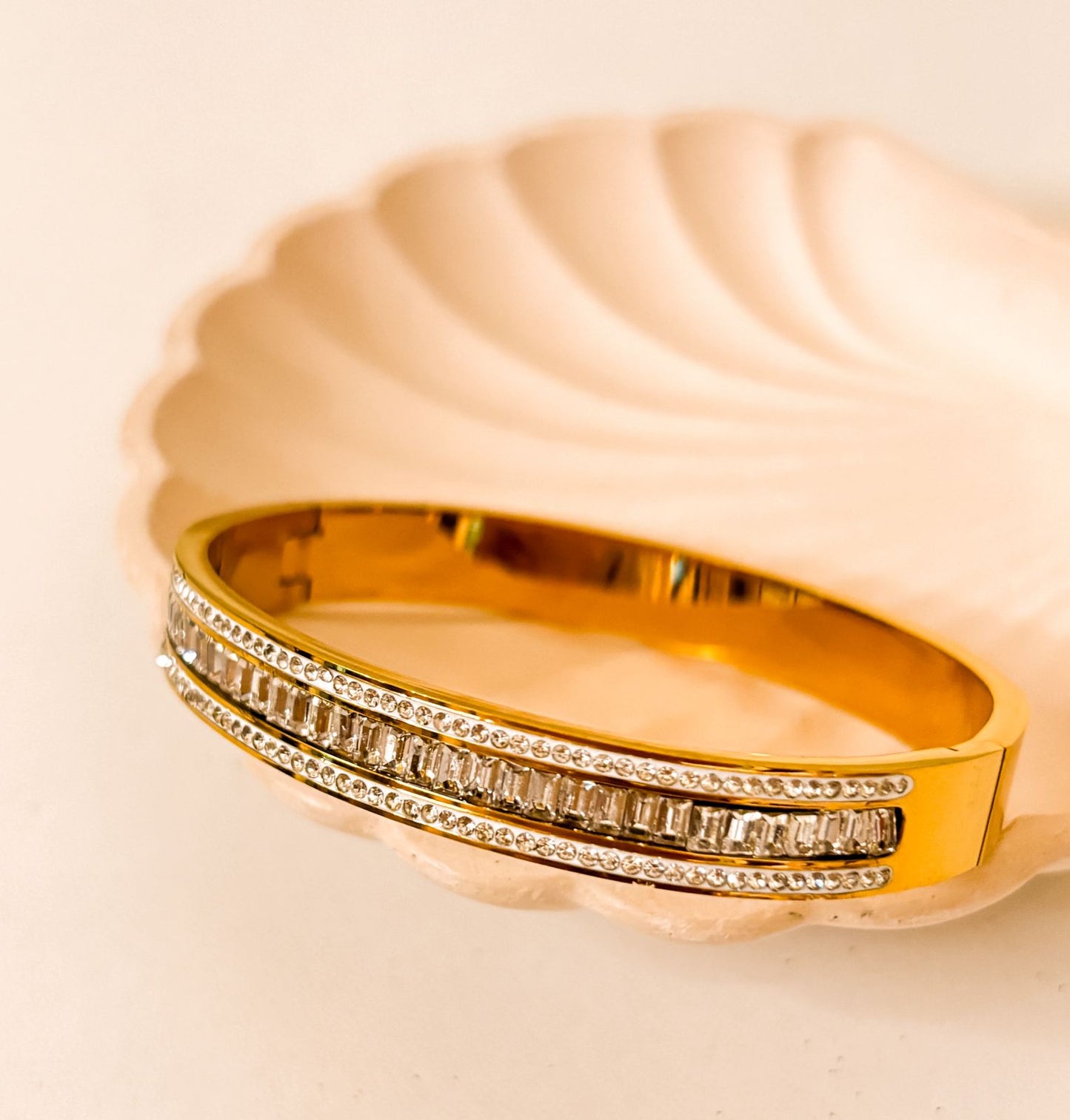 This gold-plated bangle features a luxurious triple-row design